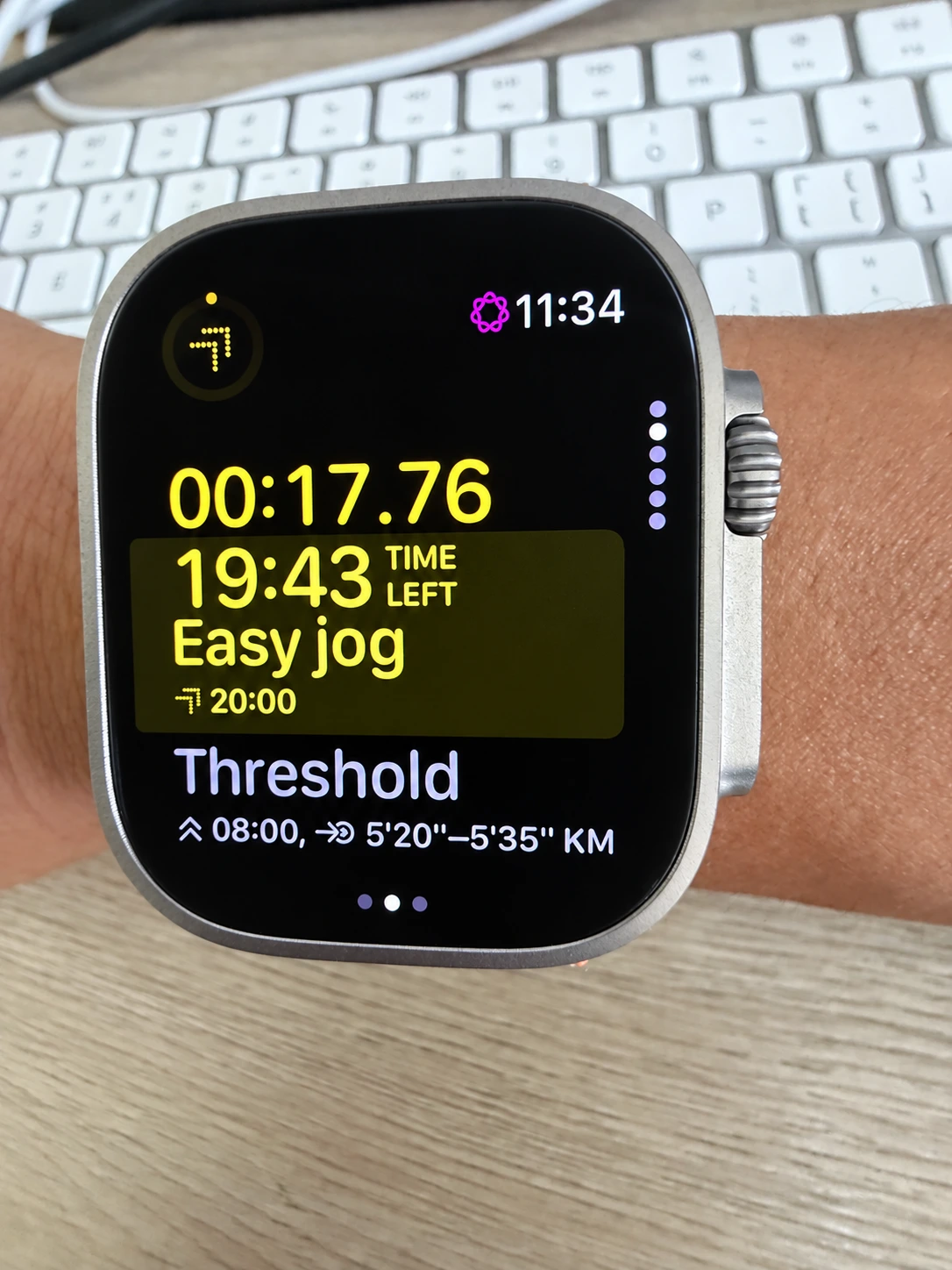 An active Apple Watch workout showing the easy-jog warm-up countdown and the next threshold step with its pace target